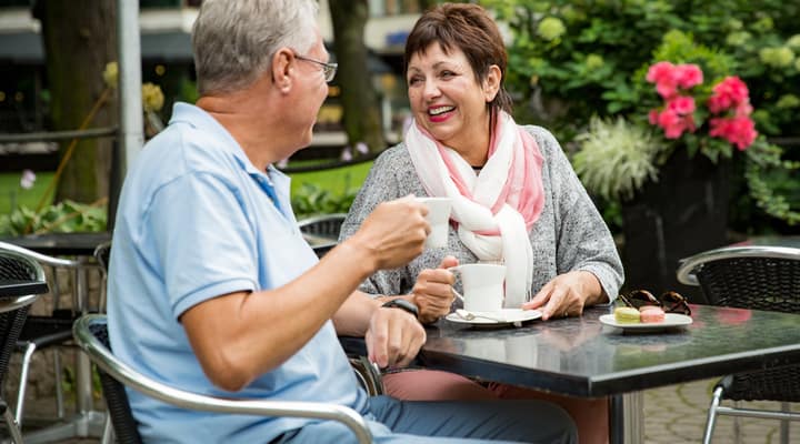 An older couple enjoying a cup of coffee outside at a café.