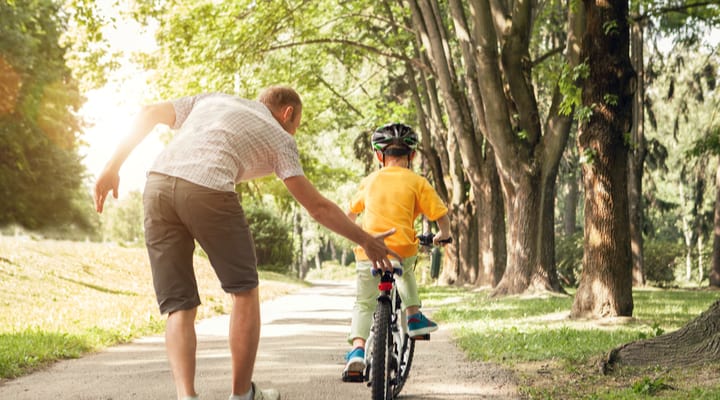 A father teaching his young son to ride a bike.