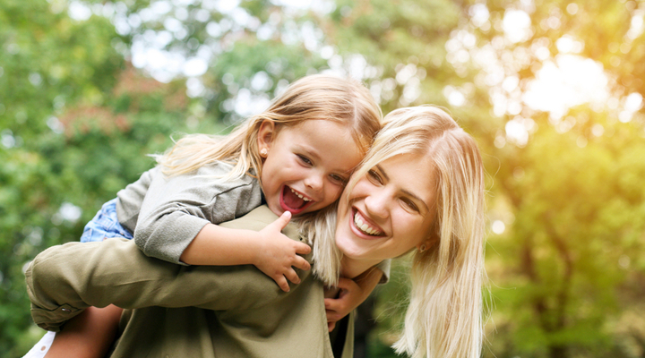 A mother giving her daughter a piggyback, and laughing together.