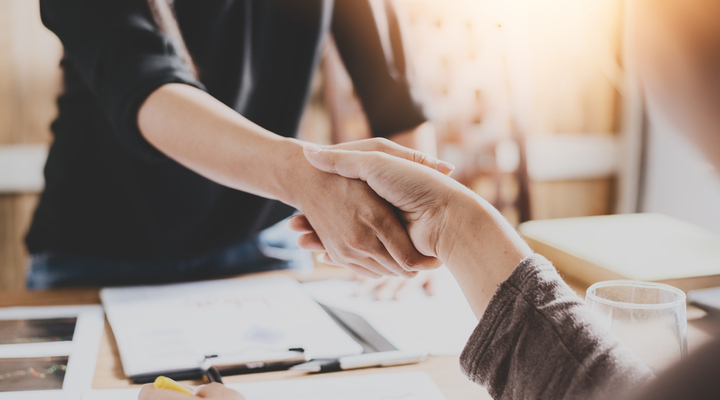 Two people shaking hands in an office.