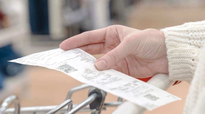 A woman looking at a receipt while shopping.