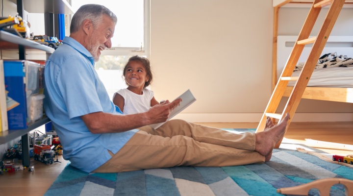 A grandfather reads to his granddaughter.