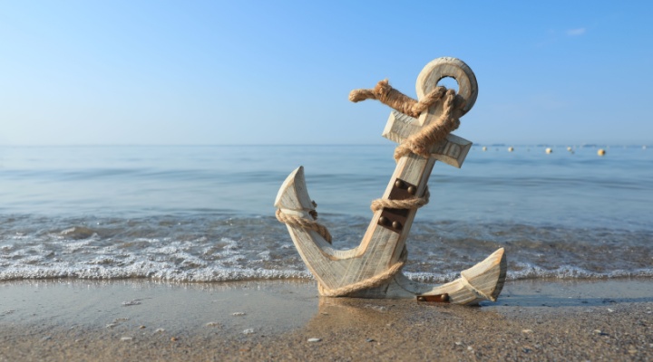 A wooden anchor on a beach.