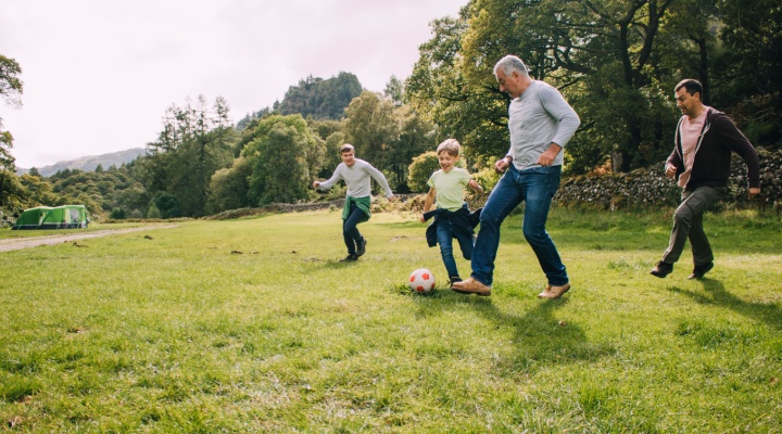 Multi-generational family playing football in a park.